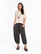 Full-body styled view of Graphite Grey Akira Barrel Pants, worn with a relaxed top and sandals.