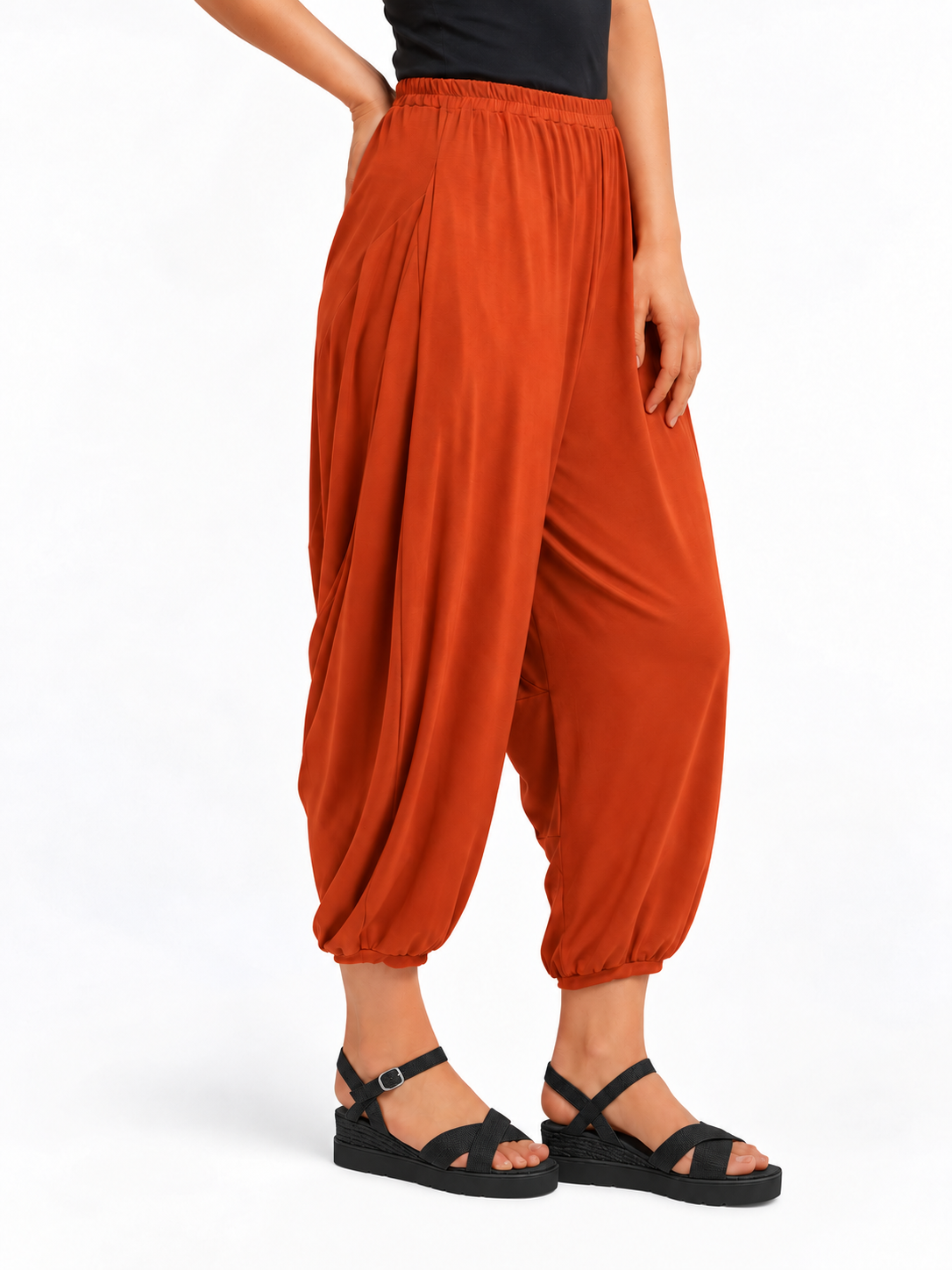 Angled side view of Rust Orange Akira Barrel Pants, showing the side drape and barrel leg shape.