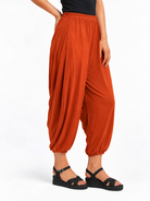 Angled side view of Rust Orange Akira Barrel Pants, showing the side drape and barrel leg shape.