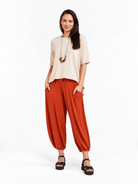 Full-body styled view of Rust Orange Akira Barrel Pants, worn with a relaxed top and sandals.