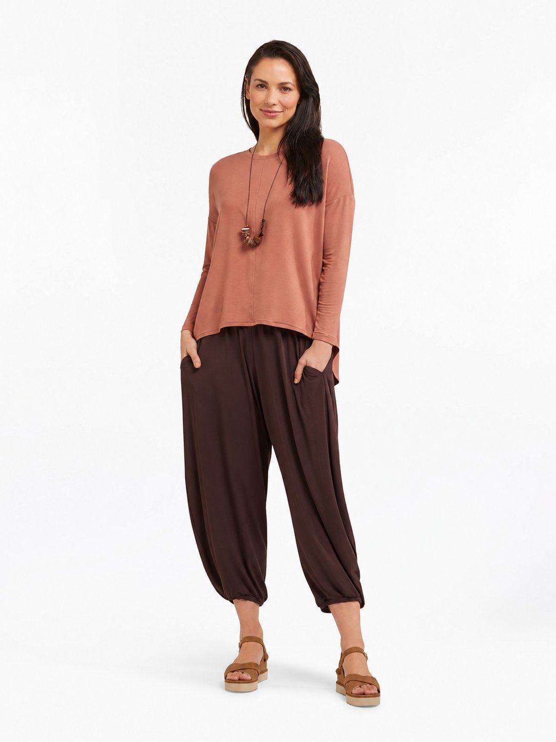 Full-body styled view of Cocoa Brown Akira Barrel Pants, worn with a relaxed top and sandals.